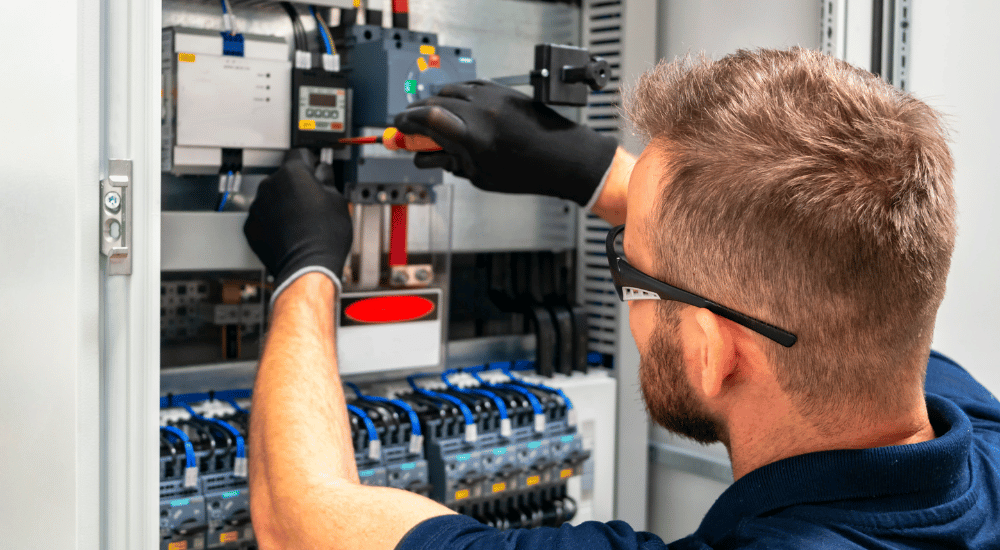An electrician installing a smart device in a home, symbolizing the integration of IoT in the electrical contracting industry.